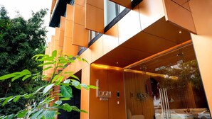 A modern hotel entrance with a glass facade, a reception desk, and a visible seating area inside. - OH | Amazing Loft Roma Nte w/ AC (Mexico City)