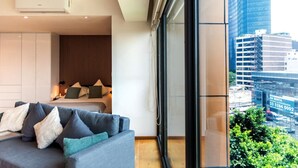 A modern hotel room with a large bed, a sofa, and a view of the cityscape. - OH | Amazing Loft Roma Nte w/ AC (Mexico City)
