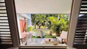 A room with a window overlooking a patio area with outdoor furniture and potted plants. - Beautiful Apart 40 m2 garden view Large swimming pool (Saint-François)