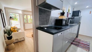 A modern kitchen with a black countertop, stainless steel cabinets, and a built-in range hood. - Beautiful Apart 40 m2 garden view Large swimming pool (Saint-François)
