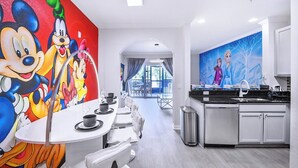 A modern kitchen with a dining area, featuring a large mural of animated characters on the wall. - Aladdin Meets Peter Pan | Disney Themed Condo (Winter Garden)