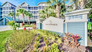 A hotel named 'PALISADES' with a sign, surrounded by palm trees and a well-maintained garden. - Aladdin Meets Peter Pan | Disney Themed Condo (Winter Garden)