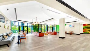 A spacious lobby with a modern design, featuring a seating area with sofas and chairs, a coffee table, and a television mounted on the wall. - Aladdin Meets Peter Pan | Disney Themed Condo (Winter Garden)