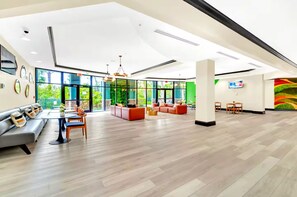 En rymlig lobby med modern design, med en sittgrupp bestående av soffor och fåtöljer, ett soffbord och en tv som är monterad på väggen.