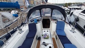 Cubierta de barco con asientos, una mesa y un timón.