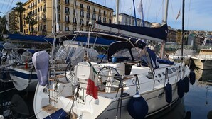 Un puerto deportivo con barcos amarrados, y un edificio con múltiples ventanas y balcones al fondo.