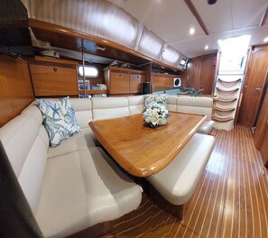 A compact interior with a wooden table, cushioned seating, and a compact kitchenette.