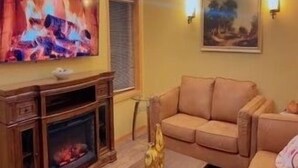 A living room with a fireplace, a sofa, and a painting on the wall.