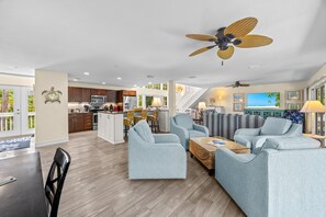 A spacious living area with a kitchen, dining space, and a seating area with sofas and a coffee table. - Slip into island time the moment you arrive at Poppy’s Paradise (Captiva)