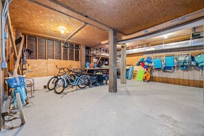 A spacious garage with bicycles, a stroller, and various storage items. - Slip into island time the moment you arrive at Poppy’s Paradise (Captiva)
