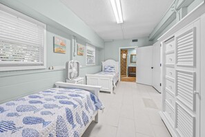 Passadís amb dos llits, un ventilador i una porta que dona a un bany.