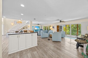 A spacious kitchen with a central island, a dining area with chairs, and a living room with sofas and a coffee table. - Slip into island time the moment you arrive at Poppy’s Paradise (Captiva)