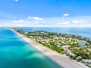 An aerial view of a coastal town with a beach, houses, and clear blue waters. - Slip into island time the moment you arrive at Poppy’s Paradise (Captiva)