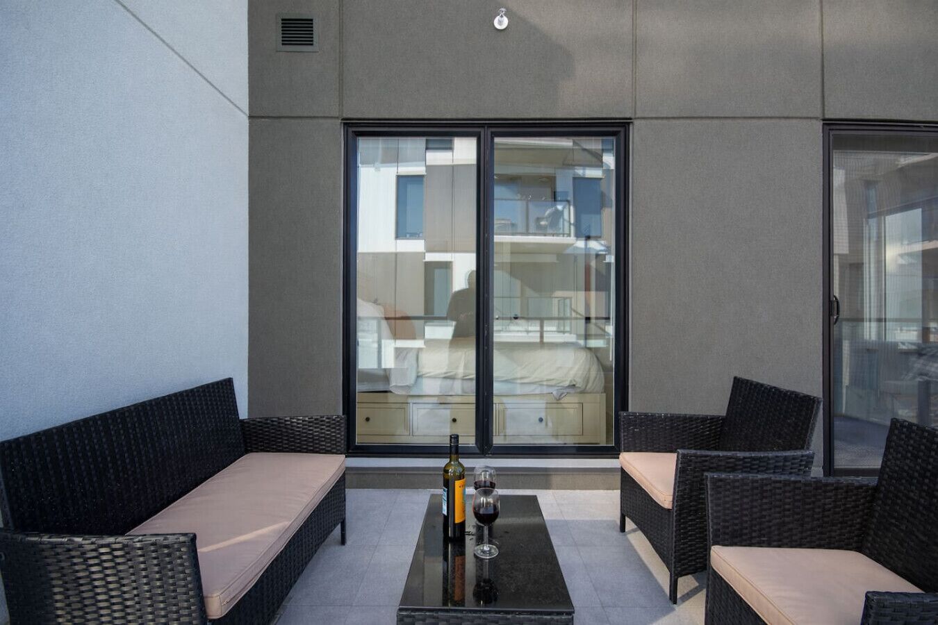 A modern outdoor seating area with wicker furniture and a glass table.