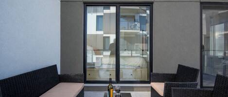 A modern outdoor seating area with wicker furniture and a glass table.
