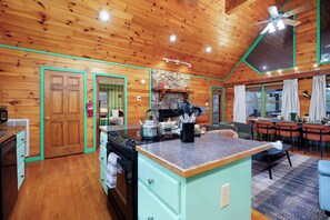A kitchen with a stove, a sink, and a dining area with chairs and a table. - Blue Ridge Retreat - Sauna - Hot Tub - Firepit (Blue Ridge)
