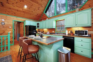 A kitchen with wooden cabinets, a central island with stools, a microwave, and a sink. - Blue Ridge Retreat - Sauna - Hot Tub - Firepit (Blue Ridge)