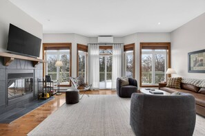 Ein geräumiges Wohnzimmer mit Kamin, großen Fenstern und einer gemütlichen Sitzecke.