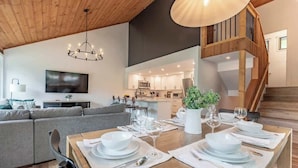Un intérieur moderne comprenant un coin repas aménagé pour deux personnes, une cuisine et un escalier.