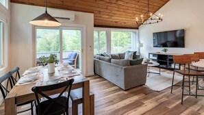 Un intérieur moderne comprenant un coin repas, un canapé, un téléviseur et un plancher en bois.