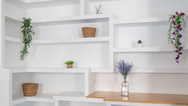 A room with white shelving units, a wooden table, and various decorative items including baskets, a small plant, and hanging flowers. - Apartment 'Mia' with Wi-Fi and Air Conditioning (Ronda)