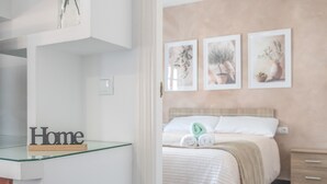 A bedroom with a bed, a bedside table, a nightstand, and a wall-mounted shelf with a 'Home' sign. - Apartment 'Mia' with Wi-Fi and Air Conditioning (Ronda)