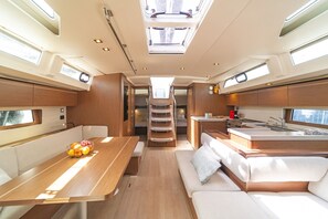 A compact interior with a dining area, kitchenette, and a small sleeping space. - Sun-Kissed Sailing Adventure in Islas Sarónicas (Alimos)