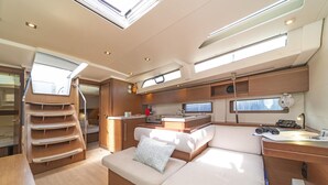 A compact, well-lit interior with a kitchenette, a seating area, and a small workspace. - Sun-Kissed Sailing Adventure in Islas Sarónicas (Alimos)