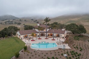 Une grande maison dotée d ’une piscine, d’un patio et offrant une vue sur le paysage environnant.