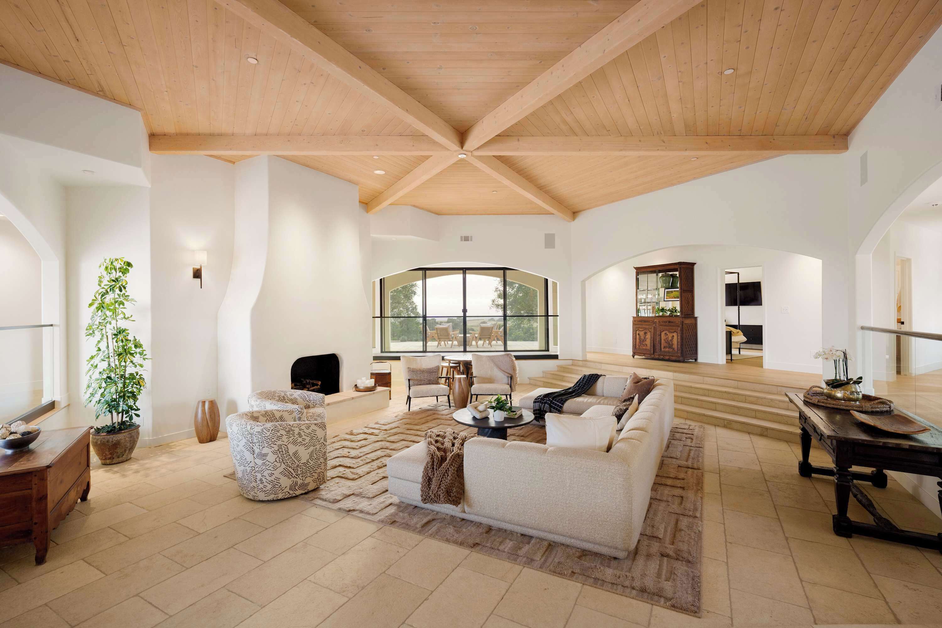 A spacious living area with a high ceiling, a large window, and a cozy seating arrangement.