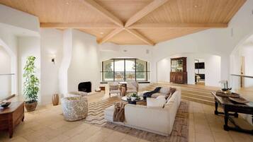 A spacious living area with a high ceiling, a large window, and a cozy seating arrangement.