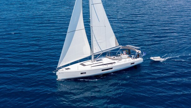 A sailboat with a cabin and a smaller boat nearby. - Sun-Kissed Sailing Adventure in Islas Sarónicas (Alimos)