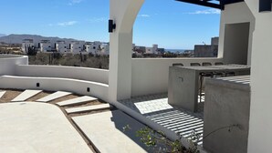 Una terrazza sul tetto con vista su edifici moderni, una pergola e una zona patio.