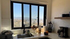 Una cucina con un'ampia finestra, un lavello, un portascopi, una macchina per il caffè e un frullatore.