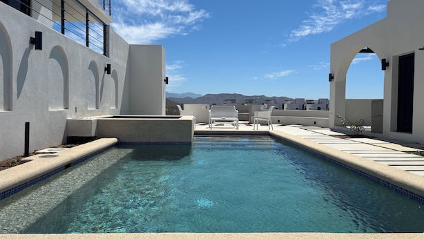 Un'area piscina con acqua cristallina, pareti bianche e vista sulle montagne.