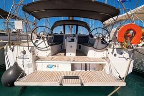A boat deck with a steering wheel, life preserver, and cabin area. - Sun-Kissed Sailing Adventure in the Dodecanese Islands (Kos)