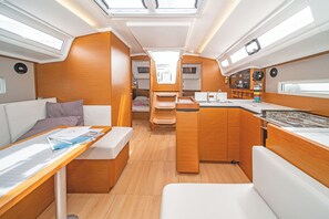 A compact interior with a kitchenette, seating area, and a small bed. - Sun-Kissed Sailing Adventure in the Dodecanese Islands (Kos)