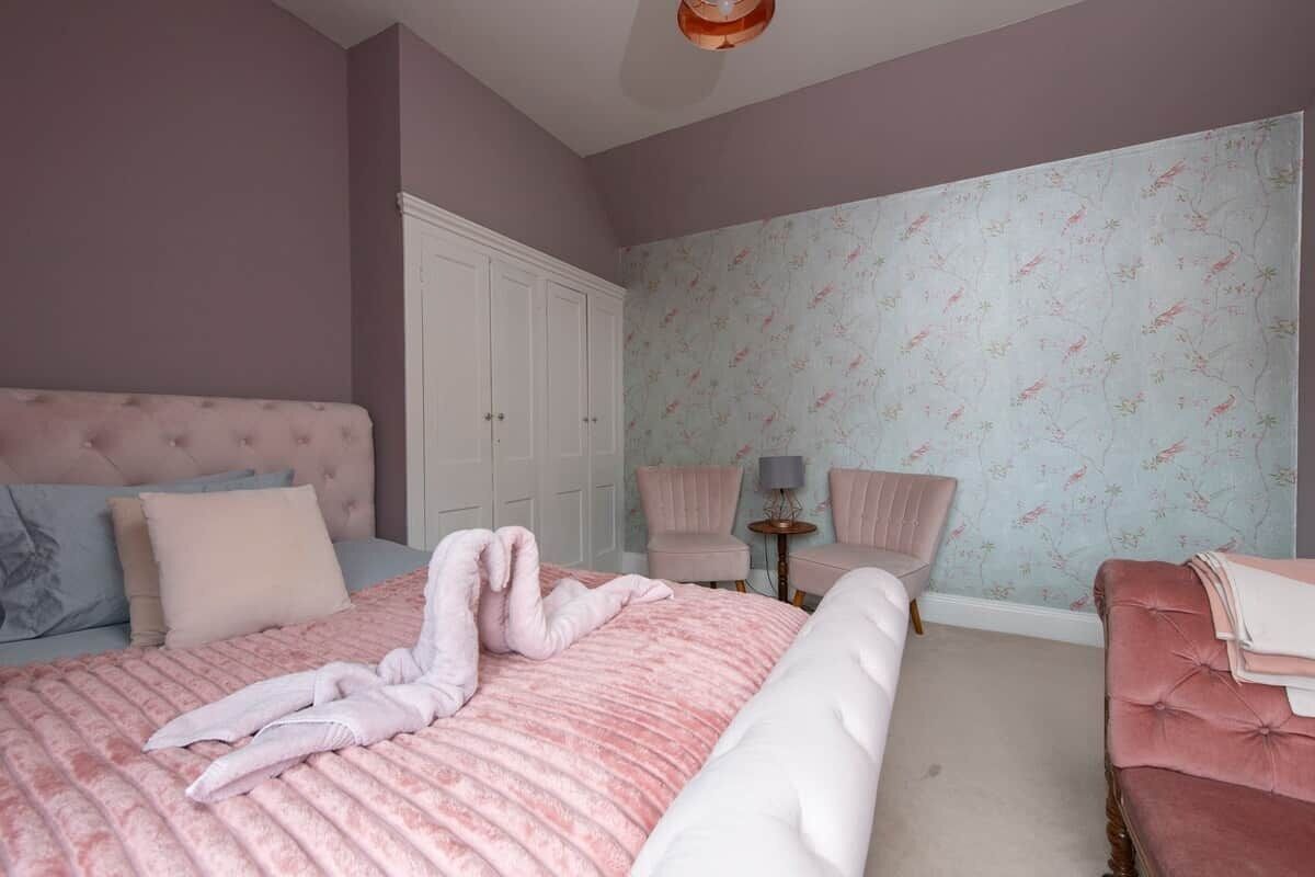 Ein Schlafzimmer mit einem Bett, zwei Stühlen, einem Kleiderschrank und einem kleinen Tisch.