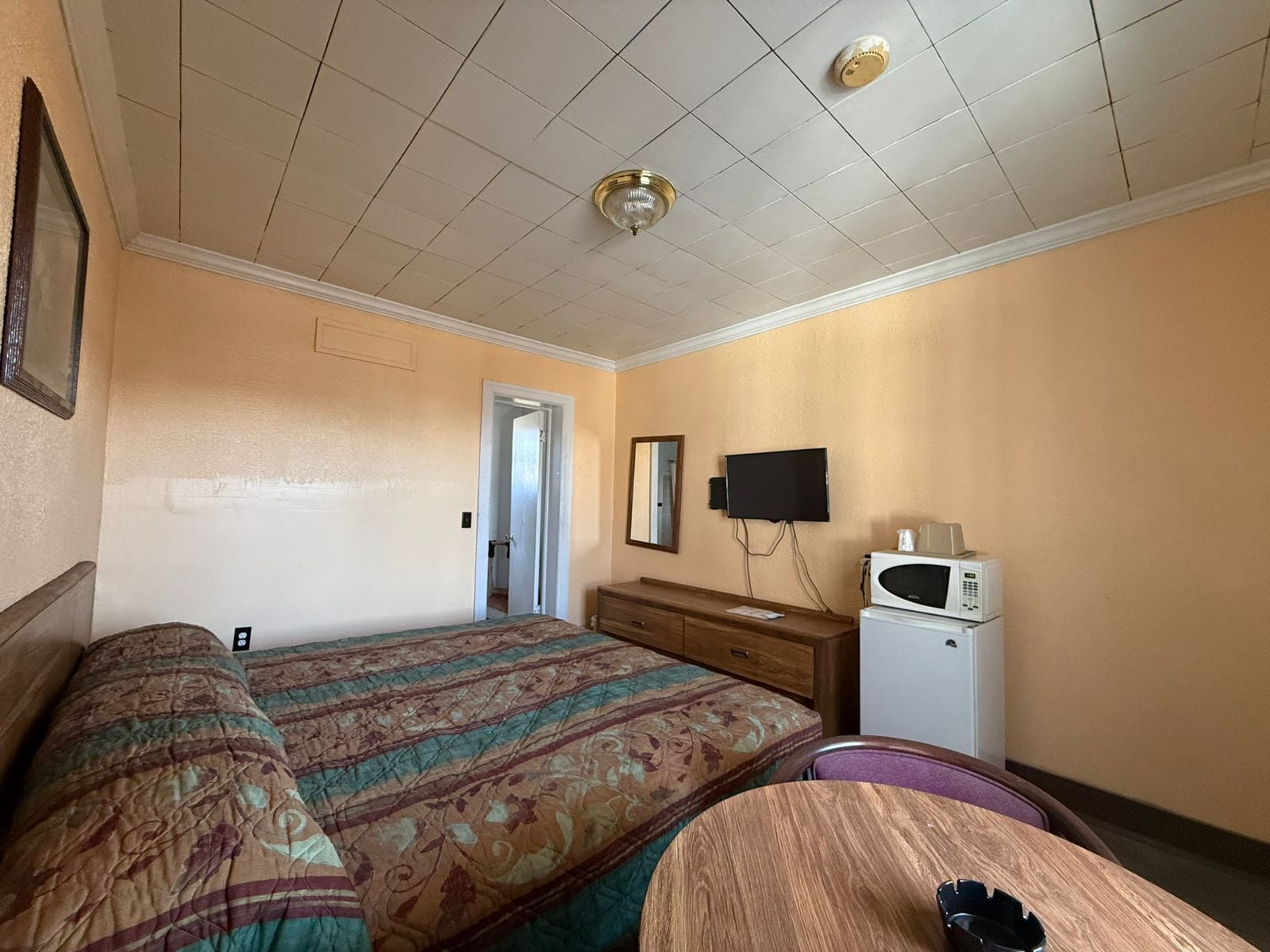 Habitación de hotel con dos camas, televisión, microondas y una puerta que da a otra habitación.