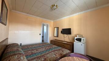 Habitación de hotel con dos camas, televisión, microondas y una puerta que da a otra habitación.