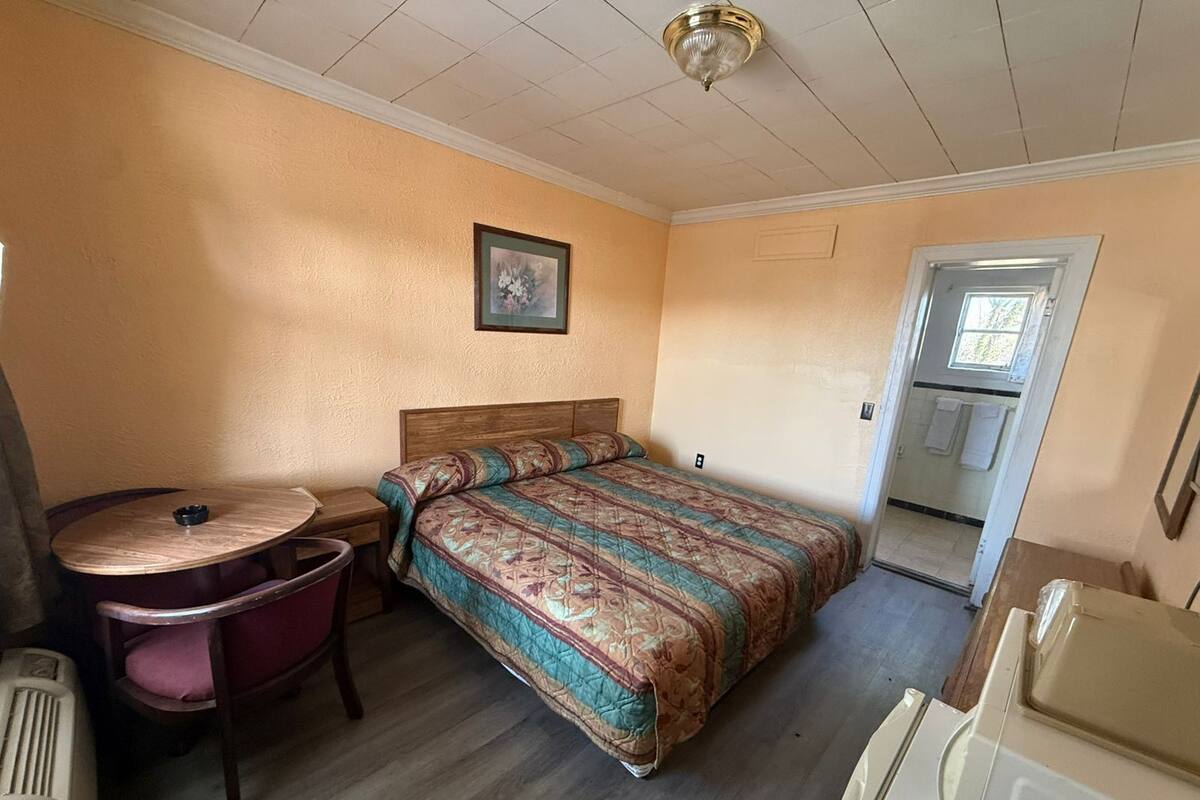A small, single-room accommodation with a bed, a desk, a chair, and a radiator.