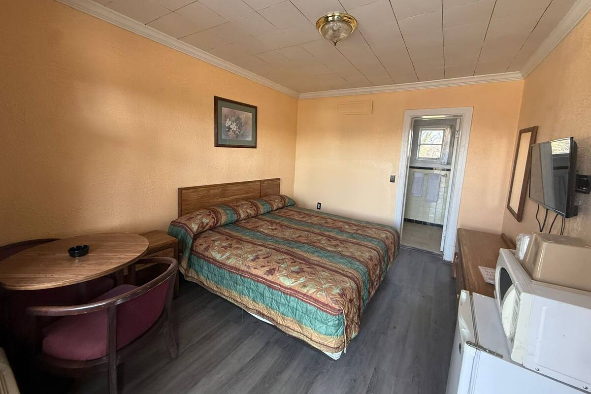 A room with a bed, a desk, a chair, a television, and a washing machine.