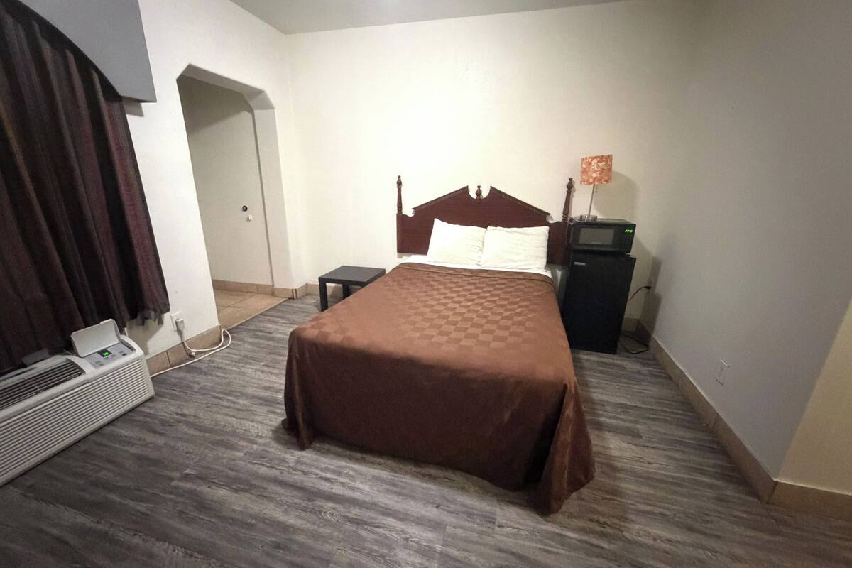 A hotel room with a bed, a heater, a small table, and a TV.