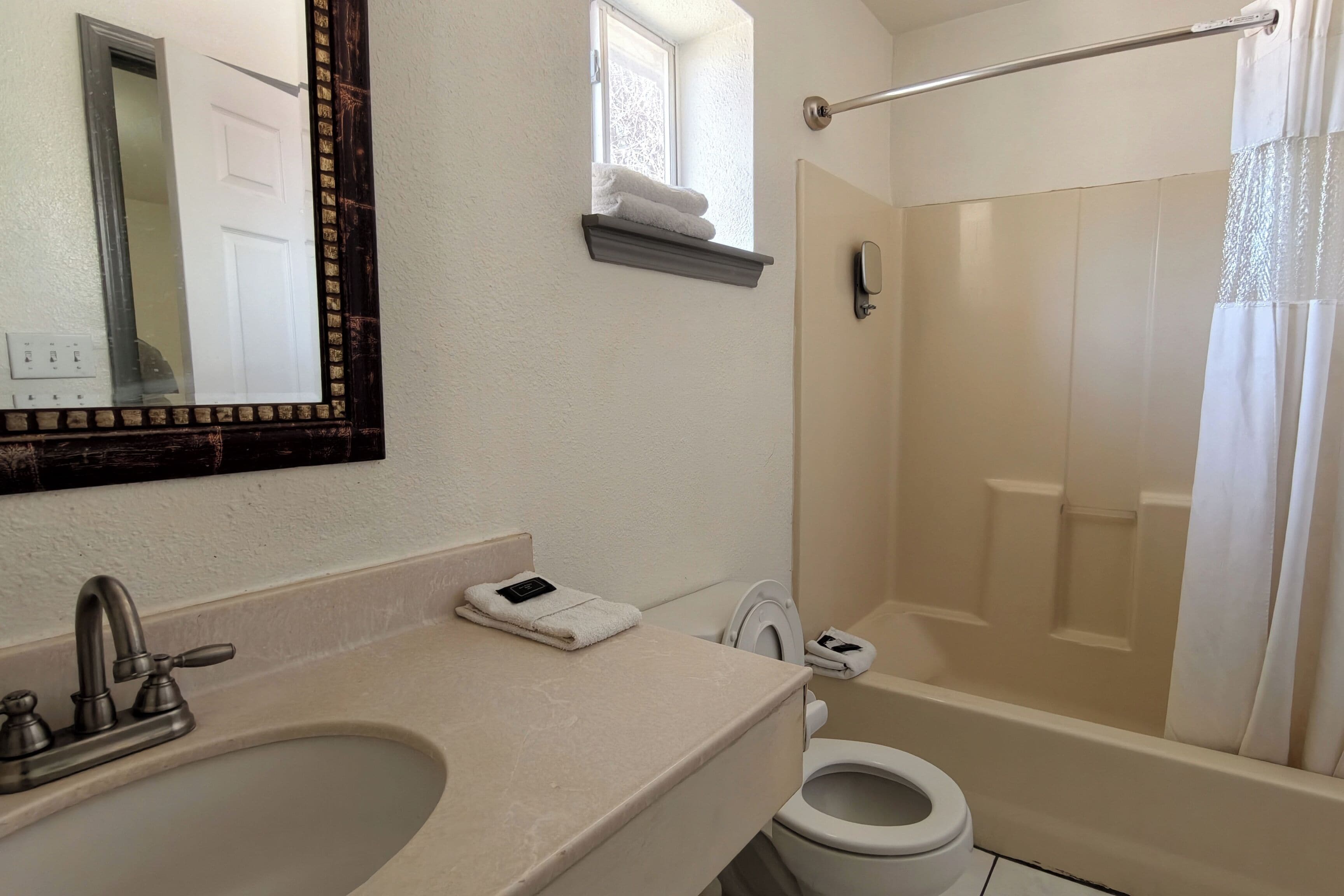 Baño con lavamanos, espejo, toallero, inodoro y ducha.