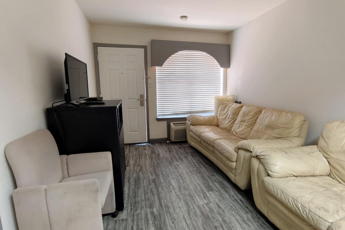 A room with a beige leather sofa, a black entertainment unit, and a white armchair.