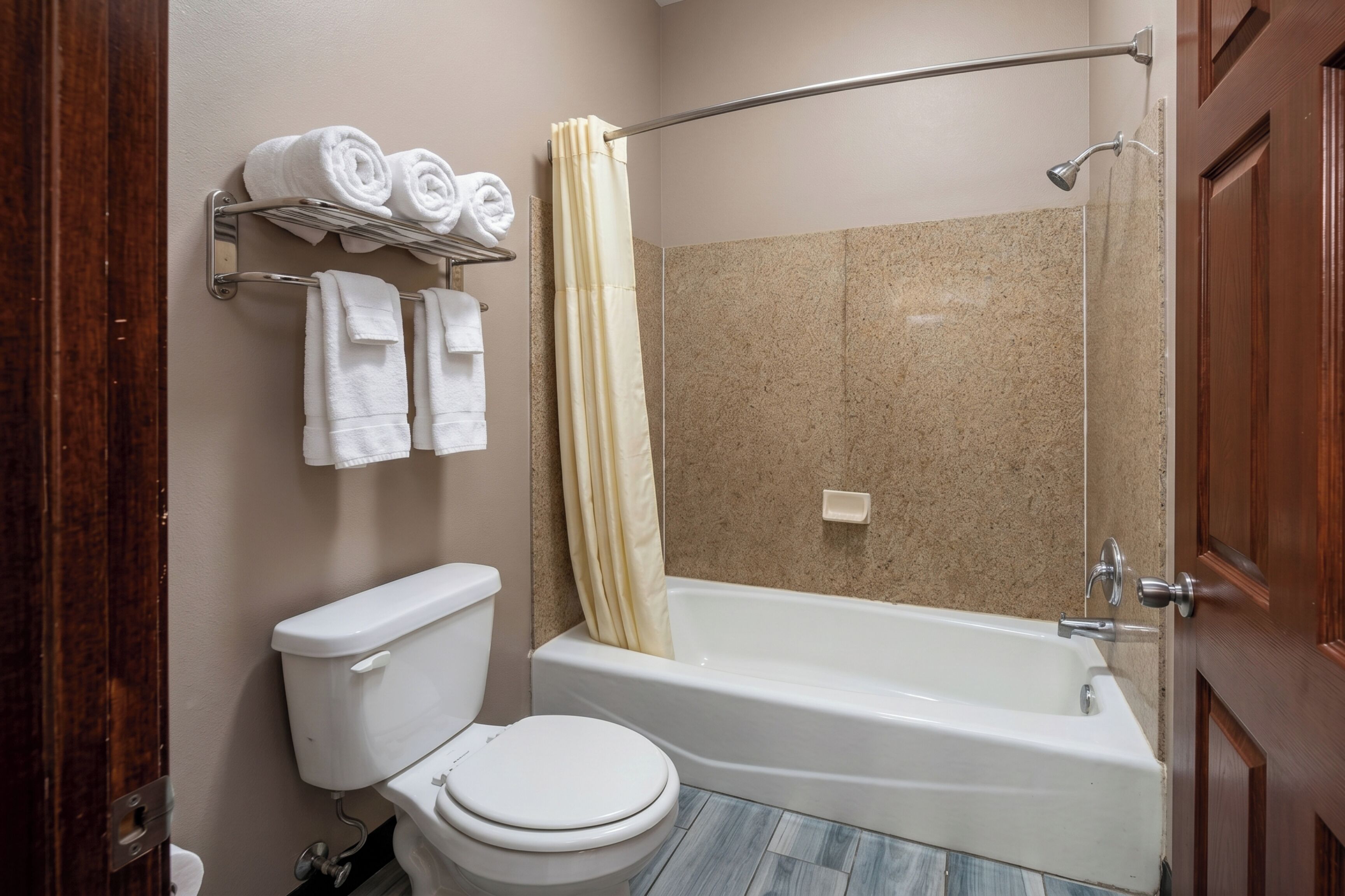 A bathroom with a toilet, a bathtub, a shower curtain, and a towel rack with towels.