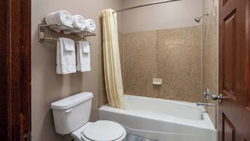 A bathroom with a toilet, a bathtub, a shower curtain, and a towel rack with towels.