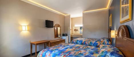 A hotel room with two beds, a desk, a television, and a mirror.