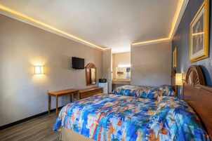 Een hotelkamer met twee bedden, een bureau, een televisie en een spiegel.