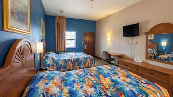 A hotel room with two beds, a desk, a chair, a television, and a window.